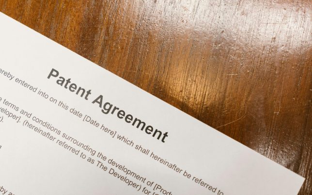 Detailed close-up of a patent agreement document on a polished wooden table.